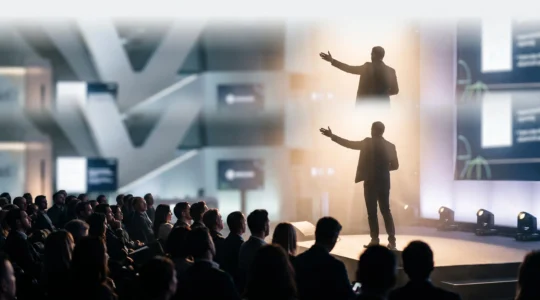 Silhouette d'un intervenant sur scène face à une audience, symbolisant la conversion d'une prise de parole en opportunités commerciales